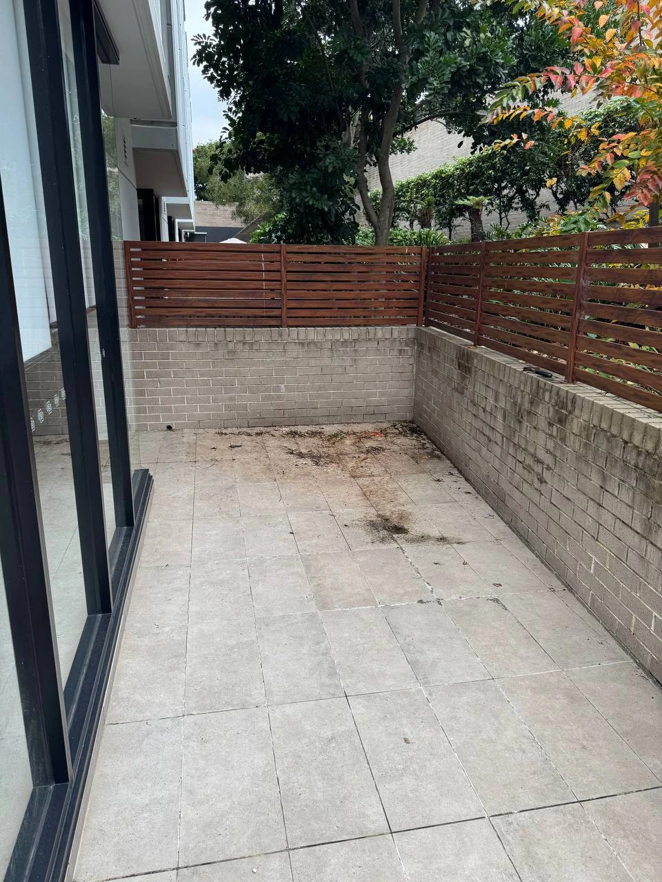 Dirty courtyard tiles with dirt and leaf stains before pressure wash — before