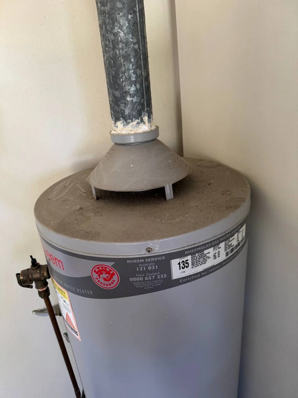 Dusty gas hot water system with dirt buildup on top before cleaning — before
