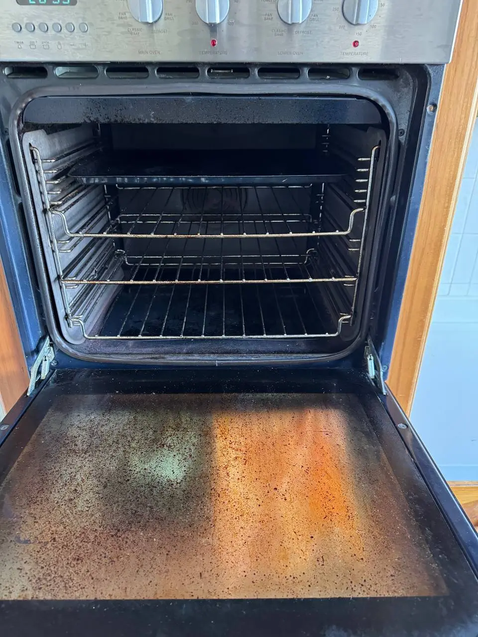 Dirty wall oven interior with heavy grease and carbon buildup before cleaning — before